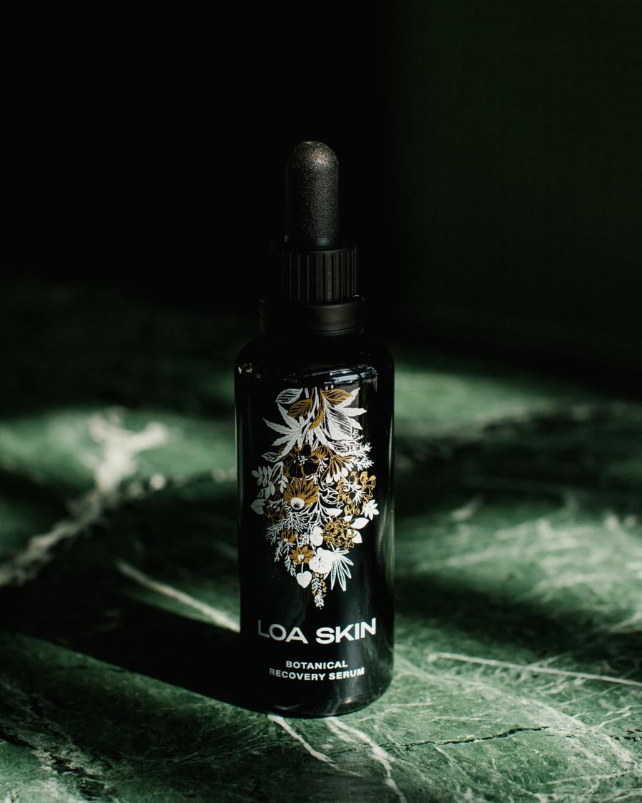 Botanical Recovery Serum in bottle on marble table.