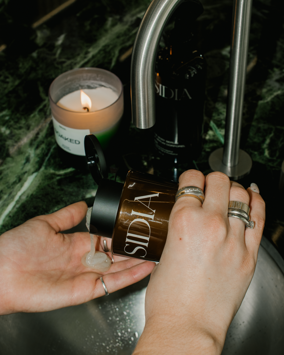 SIDIA Body Exfoliant being poured onto hand under sink - Formula Fig