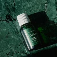 Close up of Votary Blemish Rescue Oil bottle laying on green counter.